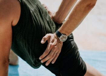 Begeleider ondersteunt een sporter bij een oefening op de mat