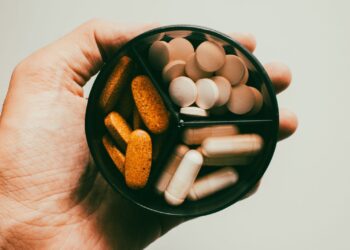 Hand met verschillende voedingssupplementen